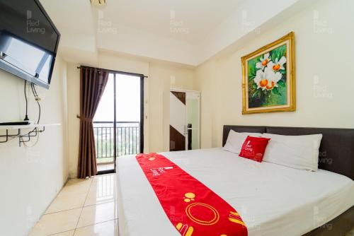 a bedroom with a bed and a tv and a window at RedLiving Apartemen Tamansari Panoramic - Santuy Agency in Bandung