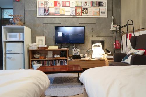 a living room with a tv and a couch and a table at Andong Poong-gyung HOSTEL n LIBRARY in Andong