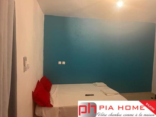 a room with a bed with a blue wall at PIA HOME Le Bajoni in Tsingoni
