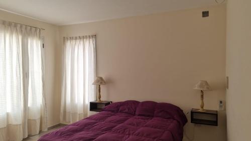1 dormitorio con 1 cama de color púrpura y 2 ventanas en Hermoso y moderno departamento a 10 cuadras de zona de bares en San Rafael Mendoza en San Rafael