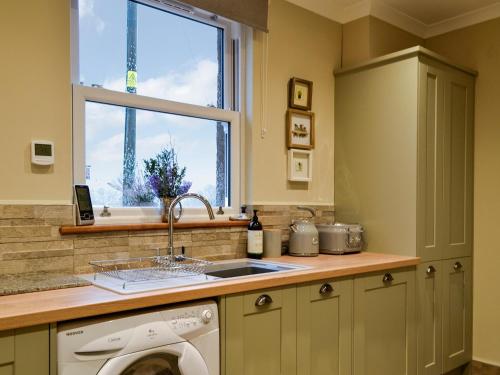 a kitchen with a sink and a washing machine at Cotlea East Cottage in Alyth
