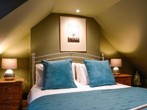 a bedroom with a bed with blue pillows at Cotlea East Cottage in Alyth