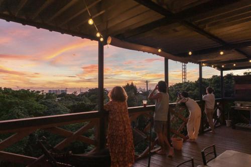 Un groupe de personnes debout sur un pont en regardant un arc-en-ciel dans l'établissement Mambo Hostel Okinawa, à Motobu