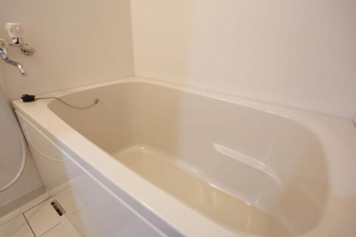uma banheira branca na casa de banho com WC em The Base Sakai Higashi Apartment Hotel em Sakai