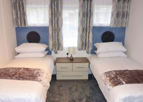 two beds in a room with two windows at Allerton Holiday Park in Arkendale
