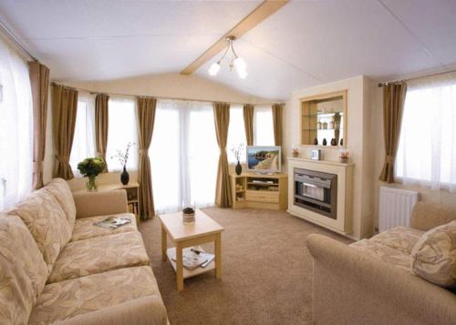 a living room with a couch and a tv at Allerton Holiday Park in Arkendale