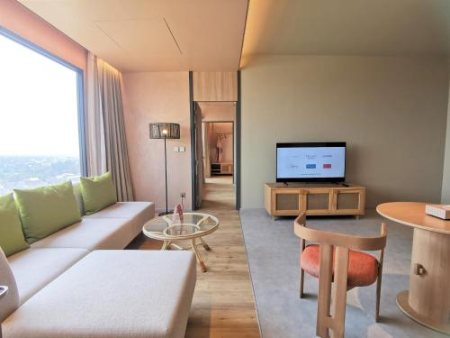 a living room with a couch and a tv at Centara Korat in Nakhon Ratchasima