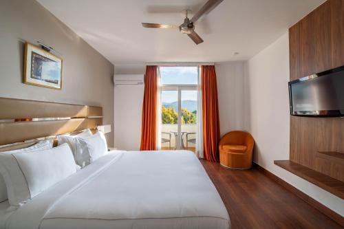 a bedroom with a large white bed and a window at Country Inn Tarika Riverside Resort Jim Corbett in Garjia