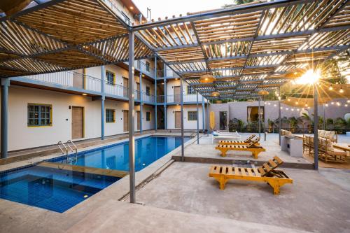 a building with a pool with benches and a building with ceilings at Zostel Goa, Morjim in Morjim