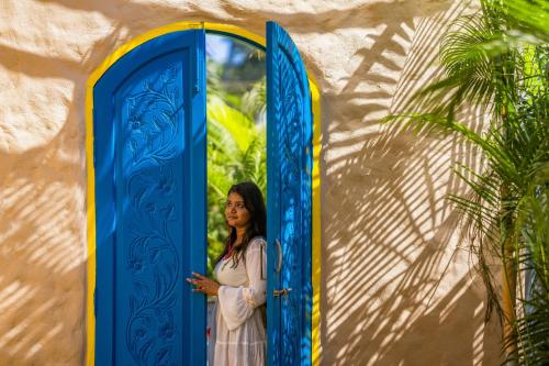 a woman standing in front of a blue door at Zostel Goa, Morjim in Morjim