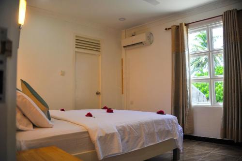 een slaapkamer met een bed met rode bloemen erop bij Asseyri Guest House in Maradhoofeydhoo