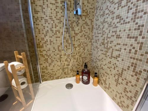 a shower with two bottles of alcohol sitting on a bath tub at DUOMO Murano Apartment with Canal view in Murano