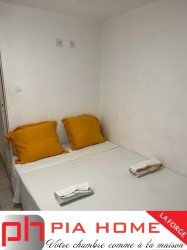 Cette petite chambre comprend un lit avec des oreillers orange. dans l'établissement PIA HOME La Forge, à Tsingoni