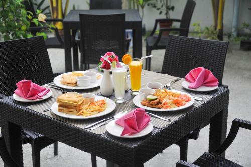 uma mesa preta com pratos de comida e sumo de laranja em Asseyri Guest House em Maradhoofeydhoo