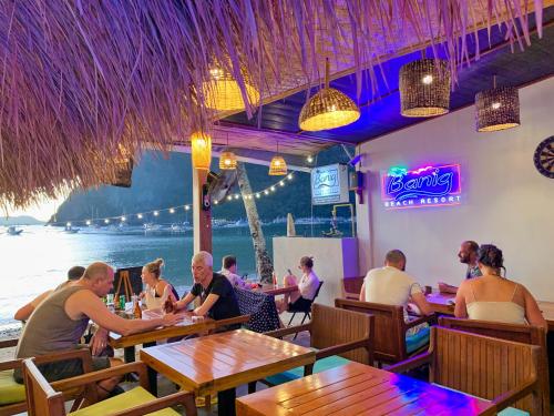 un grupo de personas sentadas en mesas en un restaurante en Banig Beach Resort El Nido, en El Nido