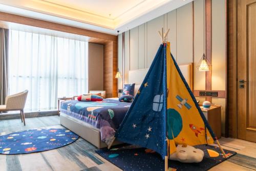 a childs bedroom with a bed and a play tent at Jingling Grand Hotel Gaochun in Gaochun