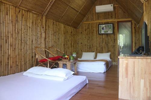 een kamer met 2 bedden en een tafel met een televisie bij Coco Island Cồn Phụng in Ben Tre