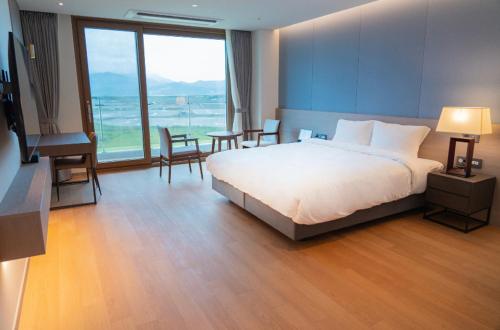 a bedroom with a large bed and a large window at Ramada Plaza by Wyndham Jaeun in Sinan