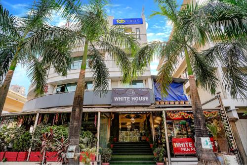 a white house with palm trees in front of it at Hotel White House - Nr MIDC Khargar in Koparpāda
