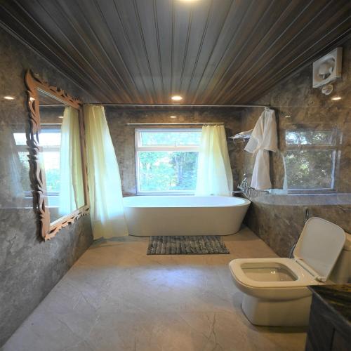 a bathroom with a bath tub and a toilet at Amaira Resort & Farms - Mirik, West Bengal in Mirik