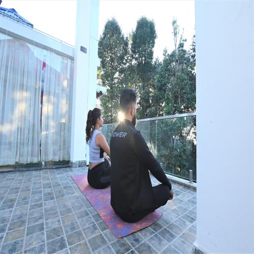 a man and a woman sitting on the floor doing yoga at Amaira Resort & Farms - Mirik, West Bengal in Mirik