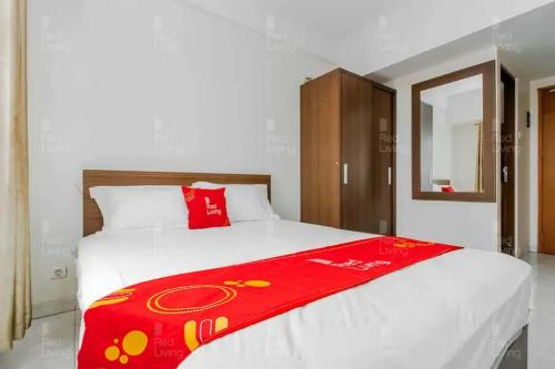 a bedroom with a bed with a red blanket on it at RedLiving Apartemen Margonda Residence 2 - Tower 2 in Pondokcina