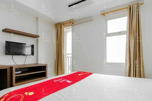 1 dormitorio con 1 cama, TV y ventana en RedLiving Apartemen Margonda Residence 2 - Tower 2, en Pondokcina