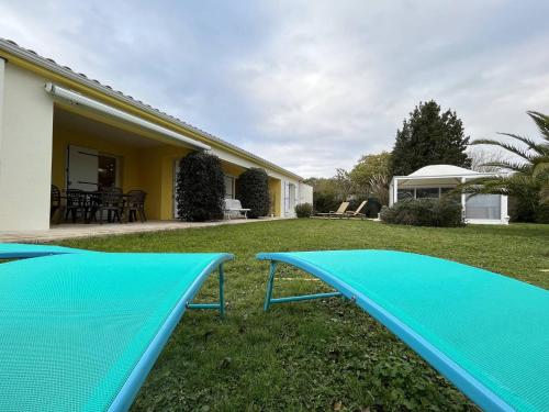 une cour avec deux trampas bleus sur l'herbe dans l'établissement Grande Maison Familiale avec SPA, Plage à Proximité, Jardin et Parking - 10 Couchages - FR-1-246A-153, à Grand-Village-Plage