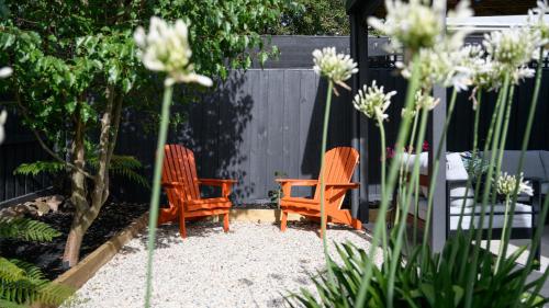 two orange chairs sitting in a garden with flowers at LACROIX - DAYLESFORD in Daylesford