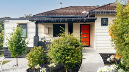 a white house with red doors and trees at LACROIX - DAYLESFORD in Daylesford