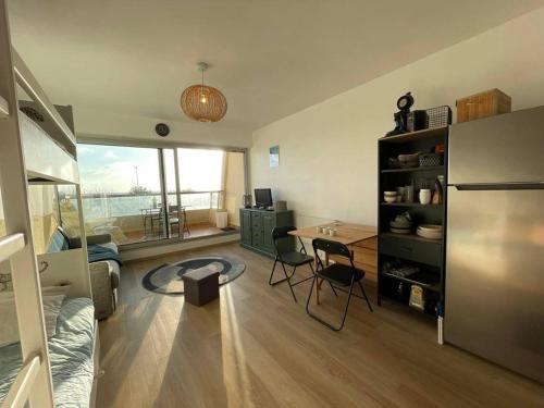 un salon avec une table et un réfrigérateur dans l'établissement Studio rénové 2* à 50m de la plage avec balcon - 4 couchages - FR-1-224C-216, à Saint-Jean-de-Monts