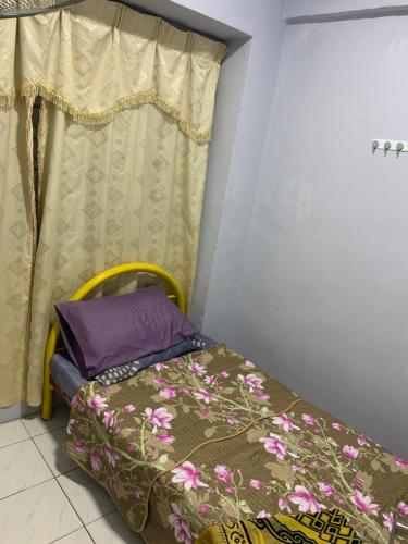 een kleine slaapkamer met een bed en een gordijn bij JoeRos Homestay in Shah Alam