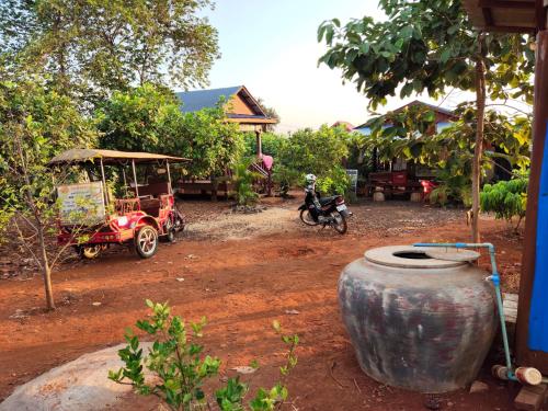 a man riding a motorcycle and a cart with a barrel at Tree Trails Homestay & Offers Jungle Trekk-Scooter For Rental in Banlung