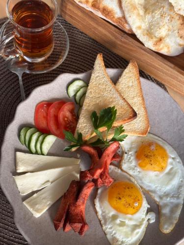 a plate of breakfast food with eggs bacon and bread at Jansyn Hotel Restaurant in Karakol