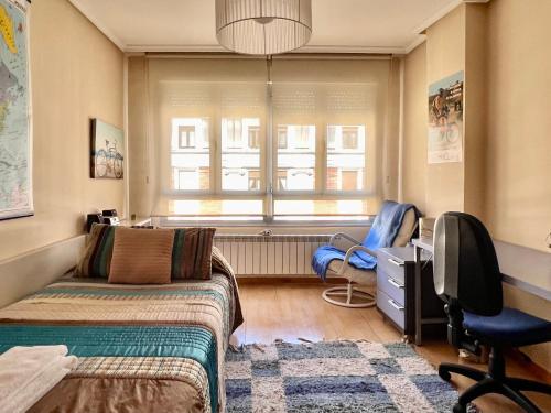 a bedroom with a bed and a chair and a window at Housingleon Ordoño II in León