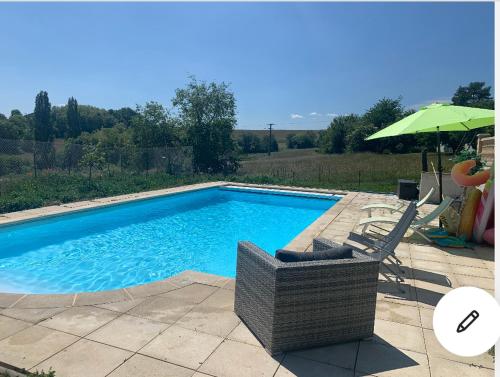 uma piscina com duas cadeiras e um guarda-sol em Maison au calme avec piscine près de Truchtersheim, à 15 minutes de Strasbourg em Durningen