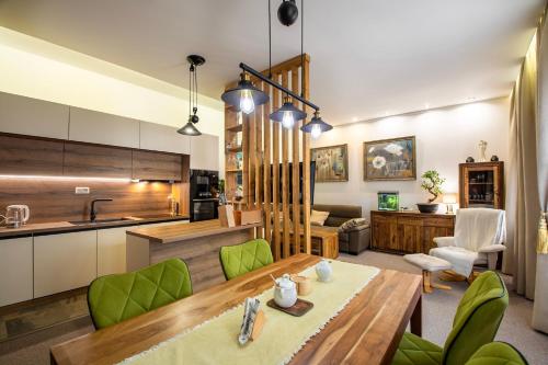 a kitchen and living room with a wooden table and green chairs at Vila Kollár Vysoké Tatry in Vysoké Tatry