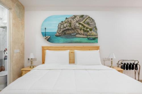 a bedroom with a large bed with a painting on the wall at Xlendi Central Apartment in Xlendi