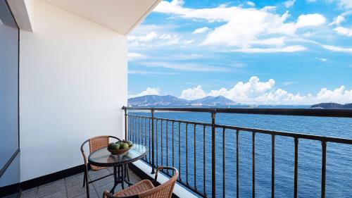 a balcony with a table and chairs and a view of the water at Hotel C Resort in Yeosu