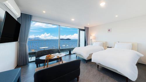 a hotel room with two beds and a large window at Hotel C Resort in Yeosu