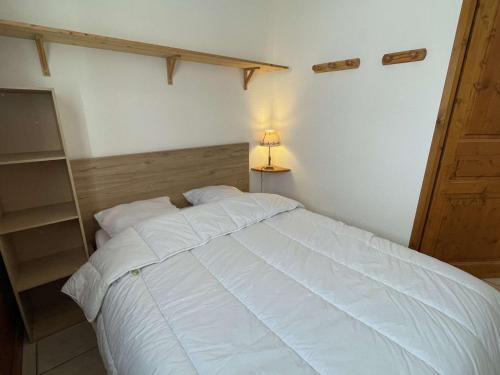Cette chambre comprend un grand lit blanc et une lampe. dans l'établissement Charmant T2 cabine avec parking à Praz-sur-Arly - 4 pers - FR-1-603-49, à Praz-sur-Arly