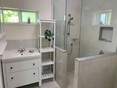 a white bathroom with a shower and a sink and a shower at Rutaki Retreat in Rarotonga