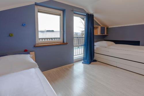 a bedroom with two beds and a window with a balcony at VacationClub – 300 Mill Pokój 5 in Szklarska Poręba