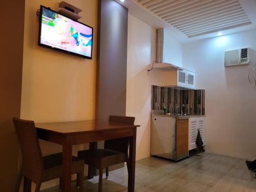 a room with a table and a television on a wall at La Belle Staycation in Puerto Princesa City