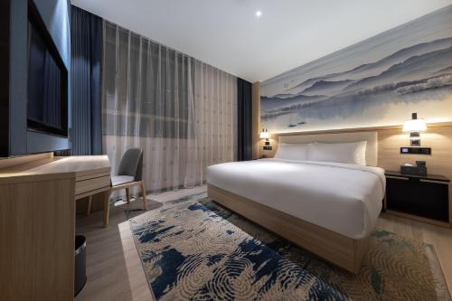 a hotel room with a bed and a flat screen tv at Ausotel by Argyle Baiyun International Airport Renhe Metro Exit B in Guangzhou