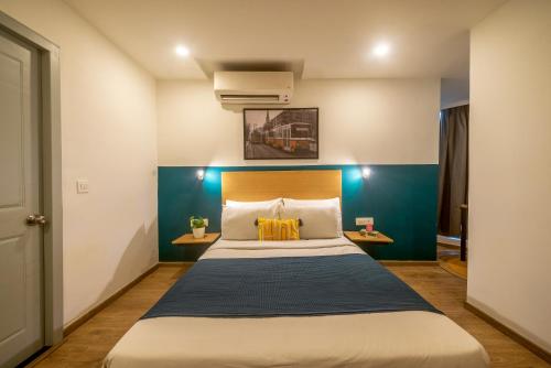 1 dormitorio con 1 cama grande y pared azul en Olive Richmond Circle - By Embassy Group en Bangalore