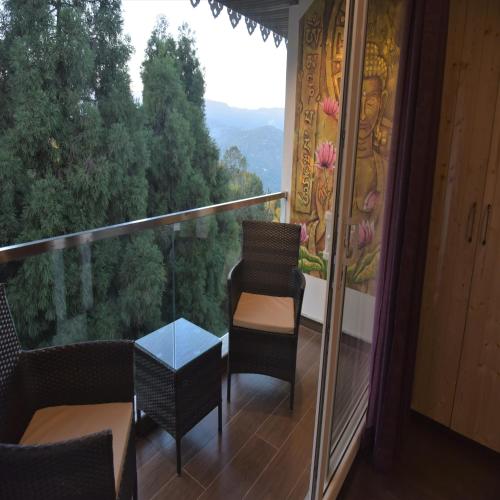 a balcony with chairs and a table and a view at Amaira Resort & Farms - Mirik, West Bengal in Mirik