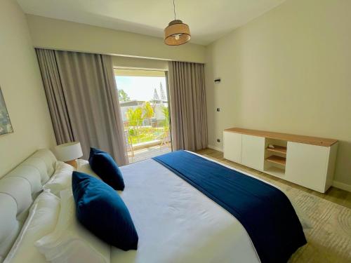 een slaapkamer met een groot wit bed met blauwe kussens bij Tropical beachfront apartment in Belle Mare