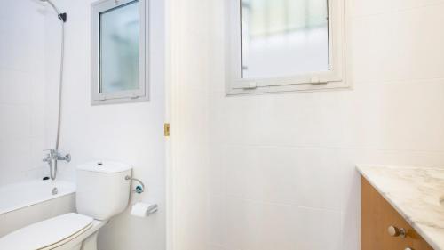Un baño blanco con inodoro y ventana. en Mas Vermey nº 4, en Calella de Palafrugell