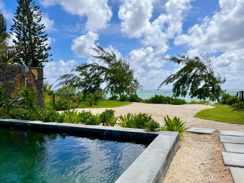 een zwembad in het midden van een tuin met een strand bij Tropical beachfront apartment in Belle Mare